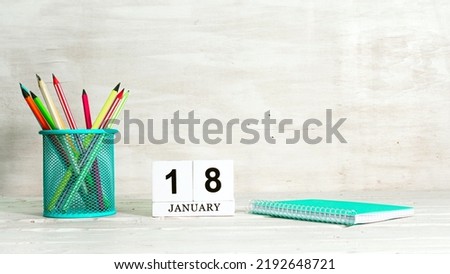 January 18 calendar. The concept of the date of the season. Pencils in a basket against the background of a notebook and the date of the month. Copy space calendar cube