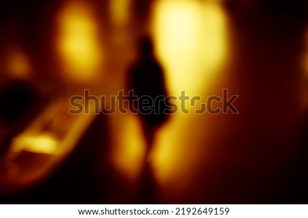 Lens blur image of a subway with moving human silhouette.
