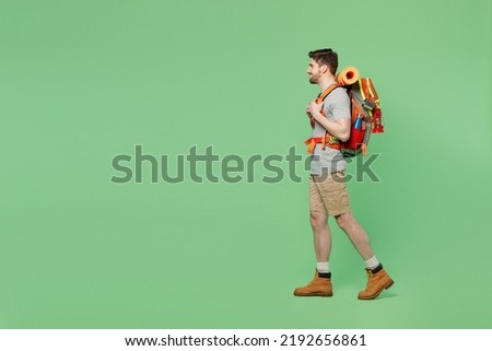 Full body side view young mountaineer traveler white man carry backpack stuff mat walk isolated on plain green background. Tourist leads active healthy lifestyle. Hiking trek rest travel trip concept Royalty-Free Stock Photo #2192656861