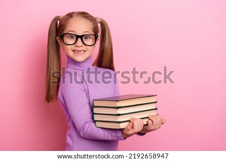 Photo of sweet lovely little girl with two tails help her teacher to hold book isolated on pink color background