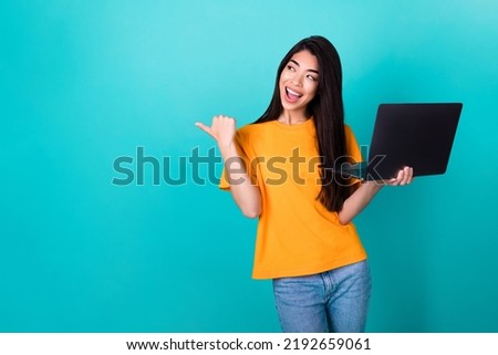 Photo of impressed millennial lady index empty space hold laptop wear orange t-shirt isolated on turquoise color background