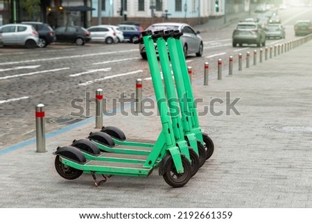 Many modern green electric scooters sharing parked city street. Self-service street transport rental service. Rent urban mobility vehicle with smartphone application. Zero emission green eco energy Royalty-Free Stock Photo #2192661359