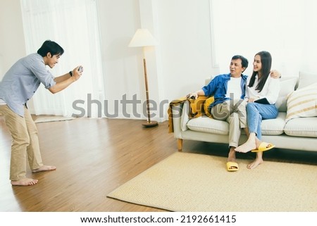Happy family : Brother takes pictures of father and sister enjoying the relationship of Asian families in the living room together for a fun photoshoot : Family day concept