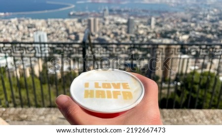 The caption I LOVE HAIFA in a cup of coffee and a view of Haifa city in the background.