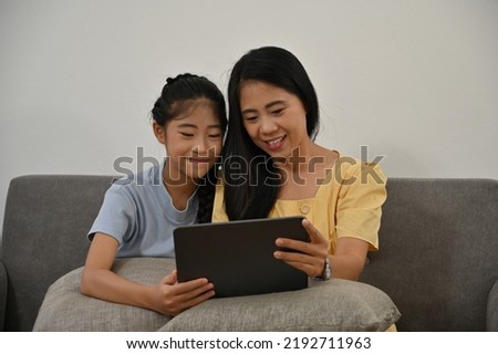 Mom and her daughter watching cartoon on digital tablet together, Happy family are spending time together, Mother's day concept.