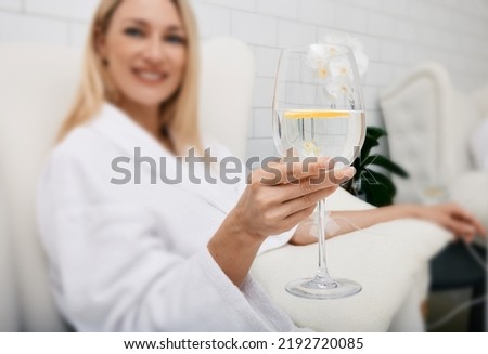 Beautiful woman with glass of refreshing lime drink during intravenous detox therapy with IV drip Infusion. Detox treatments at spa Royalty-Free Stock Photo #2192720085