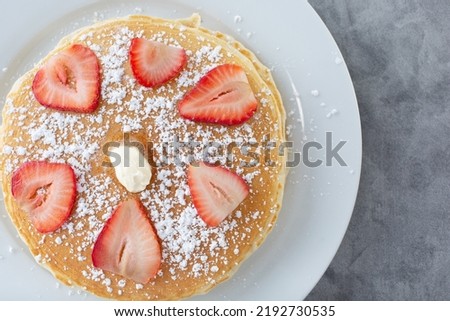A top down view of a stack of pancakes on a plate.