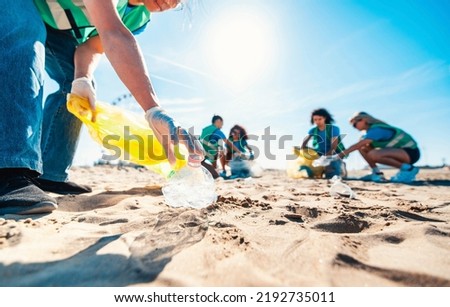 Group of eco volunteers picking up plastic trash on the beach - Activist people collecting garbage protecting the planet - Ocean pollution, environmental conservation and ecology concept Royalty-Free Stock Photo #2192735011
