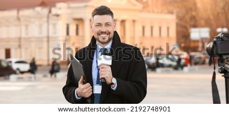 Male journalist with microphone outdoors