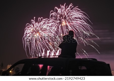 silhouette of a mother with her little daughter watching fireworks on the roof of their car Royalty-Free Stock Photo #2192749423