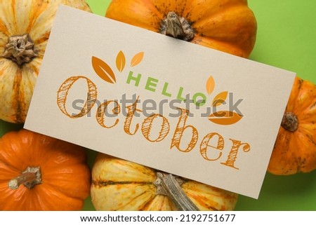 Card with text HELLO OCTOBER and autumn pumpkins on green background