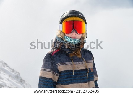 Macro portrait. Young adult woman, snowboarder or skier in a snowy winter on a mountain slope