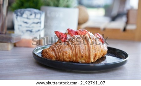 Croissant with strawberry and white softly mousse cream on blue ceramic plate with icing. French dessert assorted red berry.