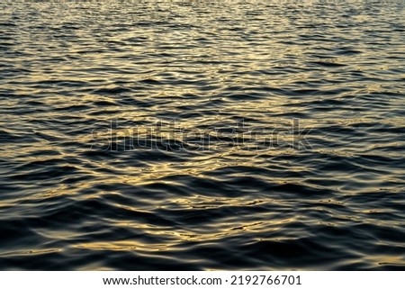 Rippled water surface of Aegean sea by sunset. Abstract, background, texture. Selective focus, noise effect and grainy texture. 