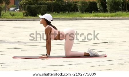 Photo of young amazing sports black woman make stretching exercises outdoors on the street.