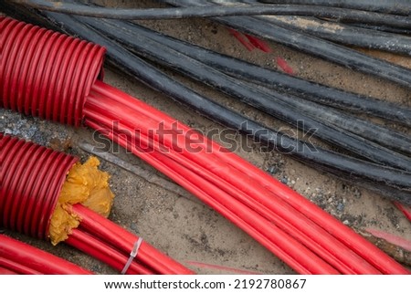 Network cables in red corrugated pipe are buried underground on the street. underground electric cable infrastructure installation. Construction site with A lot of communication Cables Royalty-Free Stock Photo #2192780867