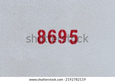 Red Number 8695 on the white wall. Spray paint.
