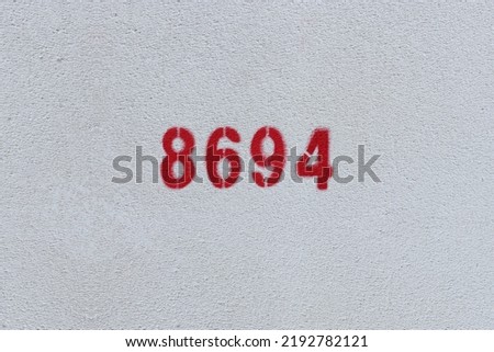 Red Number 8694 on the white wall. Spray paint.
