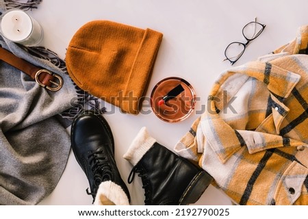 Stylish warm closes and accessories, top view. Leather boots, checkered warm shirt, knitted hat and other items on the white background, top view