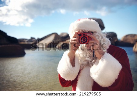 Father Christmas on a beach taking a picture with copyspace