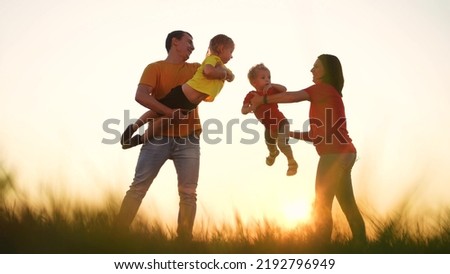 happy family play in the park with children. mom and dad bathe children in their arms and play outdoors a in the park. happy family kid dream concept. fun healthy family playing in garden silhouette