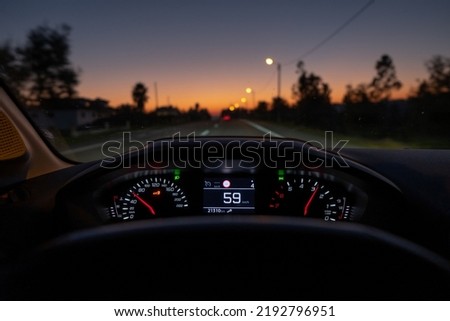 Driver view to the speedometer at 59 kmh or 59 mph, on a road blurred in motion, night fall view from inside a car of driver POV of the road landscape. Royalty-Free Stock Photo #2192796951