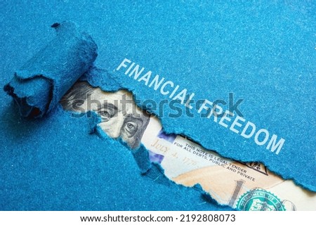 The inscription financial freedom on torn paper and dollars under it. Royalty-Free Stock Photo #2192808073