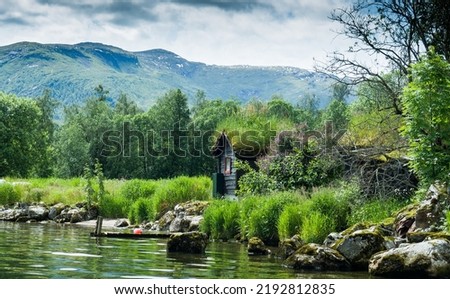 Norwegian Lake with a small boathouse and clouds rolling over the hills Royalty-Free Stock Photo #2192812835