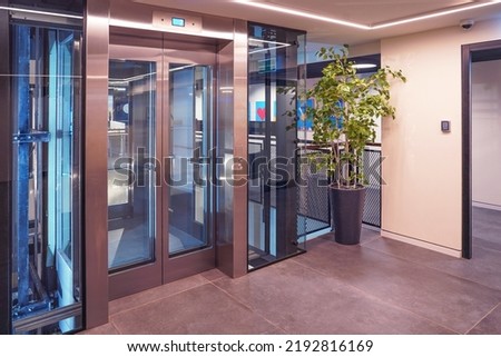 Glass elevator doors in office building. Wide angle view of modern elevators with doors. Elevators in business centre or modern floor Royalty-Free Stock Photo #2192816169