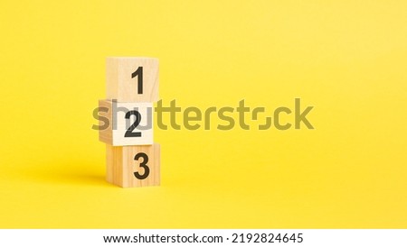 numbers 123 on wooden cubes standing on top of each other, yellow background