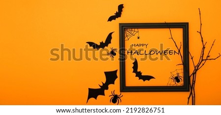 Halloween background. Black bats, spiders, branches and black frame with text on orange background flat lay with copy space.	