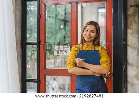Young Asian freelancer coffee shop owner standing with open sign, standing front of the door.