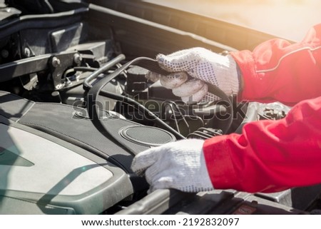 Car timing belt in the hands of an auto mechanic. Under the hood replacing the belt. Timely maintenance in a car service Royalty-Free Stock Photo #2192832097
