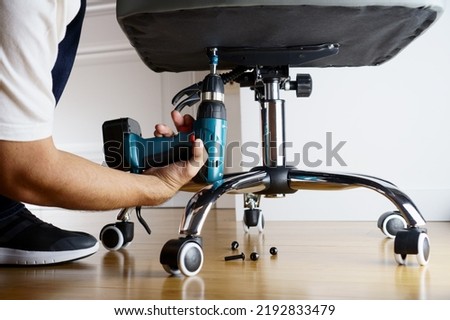 Master repairs office chair with a screwdriver                                Royalty-Free Stock Photo #2192833479