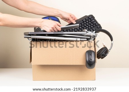 Female hands put tablet computer and keyboard in box full old used computers and gadget devices for recycling. Planned obsolescence, e-waste, donation, electronic waste for reuse and recycle concept Royalty-Free Stock Photo #2192833937