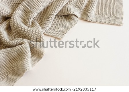 Beige knitted blanket on beige  background with copy space.Autumn, winter  template.Flat lay, top view