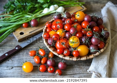 Cherry tomatoes are in the basket on a rough wooden table. Vegetables for salad preparation. Royalty-Free Stock Photo #2192847395