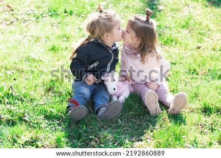 Cute kids love. Little girl kissing little boy outdoors in park. Children in beautiful spring green field.