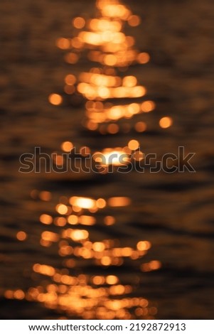 Awe beautiful vibrant orange shallow sun path of round highlights spot particles on sea out of focus area. Summer travel scene