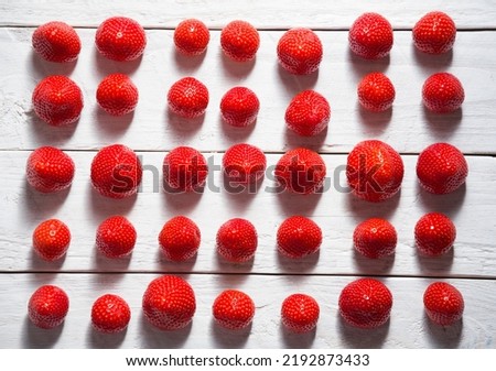 abstract pattern of red fresh strawberries laid out on a white board background 