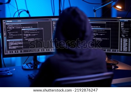 cybercrime, hacking and technology concept - hacker in dark room writing code or using computer virus program for cyber attack Royalty-Free Stock Photo #2192876247