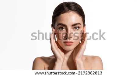 Beauty face and spa. Woman with freckles, clean nourished skin, biting lip and look aside. Girl model using antiaging cosmetics and vitamin c serum for bettet smoother skin tone, white background Royalty-Free Stock Photo #2192882813