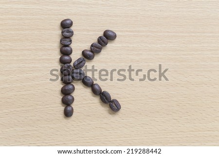 Coffee beans of alphabet placed on the wood background.
