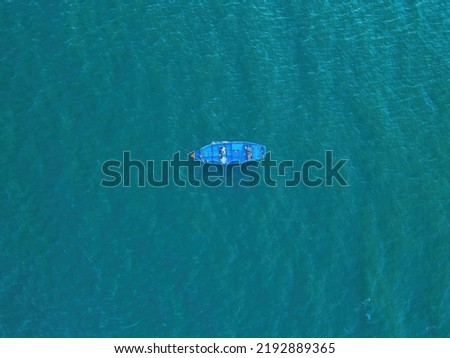Top view, aerial view wooden fishing boat on the beach from a drone. Royalty high quality stock photo image of the wooden fishing boat on the beach. Fishing boat is mooring on clear blue beach alone