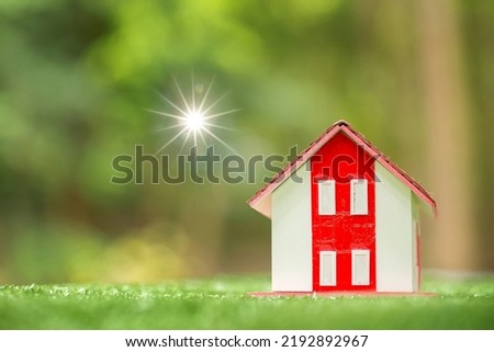 Environmentally eco-friendly real estate house. Small model building property home on grass in green nature ecology. Sustainable energy conservation residential design and sell - rent business concept