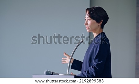 Asian middle aged woman giving a lecture and audience.