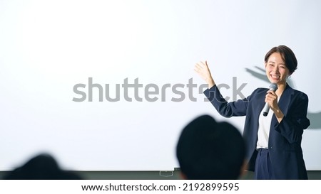Asian middle aged woman giving a lecture and audience. Royalty-Free Stock Photo #2192899595