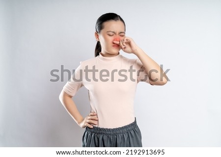 Asian woman was sick with fever, sneezing and rubbing her nose with red spot, standing isolated on white background. Royalty-Free Stock Photo #2192913695