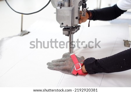 Cutting garment, close up photo of the process of cutting fabric in a garment factory
