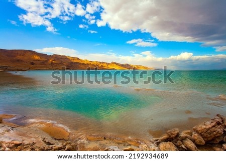Israel. The picturesque and magnificent Dead Sea. Winter thunderstorm begins. Low winter clouds are reflected in the green sea water. The healing waters of the Dead Sea